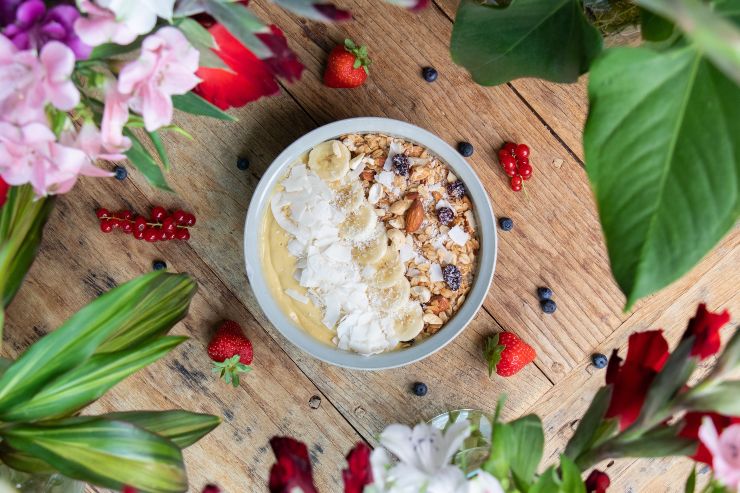 Vista dall'alto di una smoothie bowl con frutta e granola su un tavolo di legno