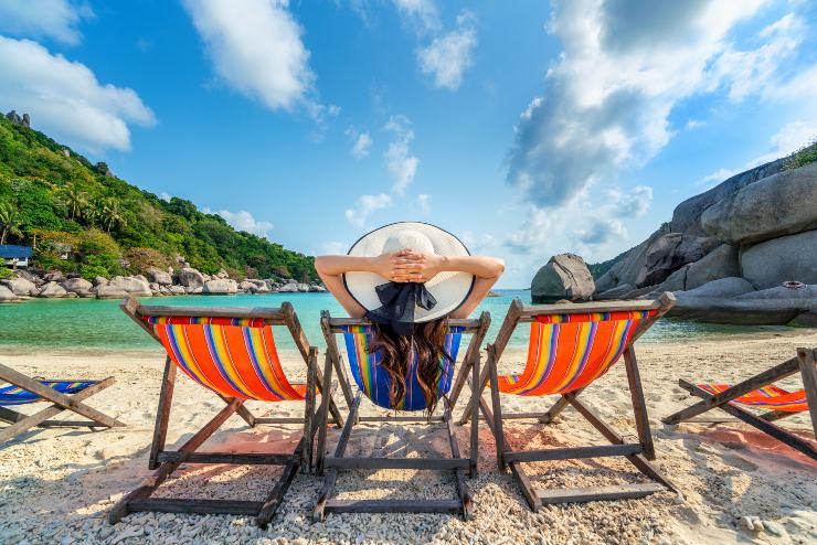 Una persona seduta su una sdraio in spiaggia davanti al mare