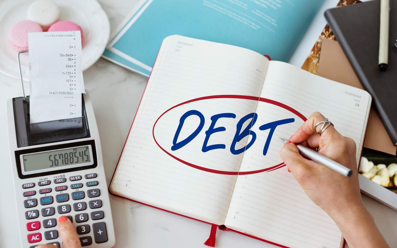 Un quaderno con la scritta debito accanto ad una calcolatrice