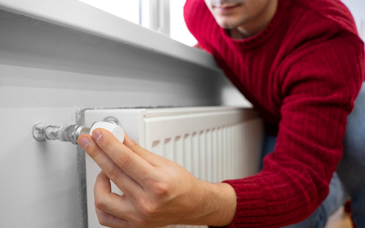 Una persona impegnata a spegnere un termosifone