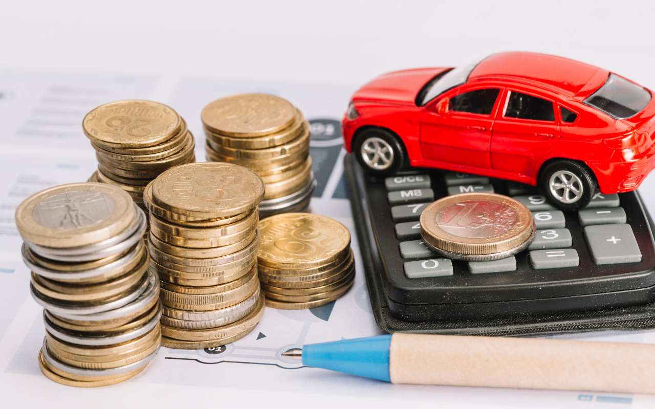 Modellino di un'auto, calcolatrice, penna e monete su un tavolo