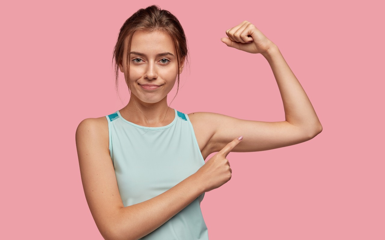 Una ragazza sportiva che indica il tricipite