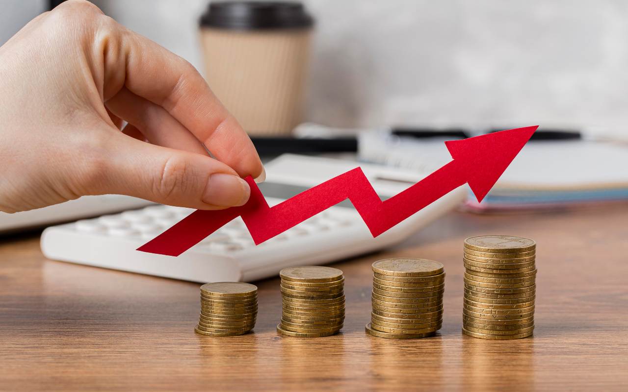 Concetto di investimento finanziario con una mano che tiene una freccia rossa verso l'alto sopra delle monete