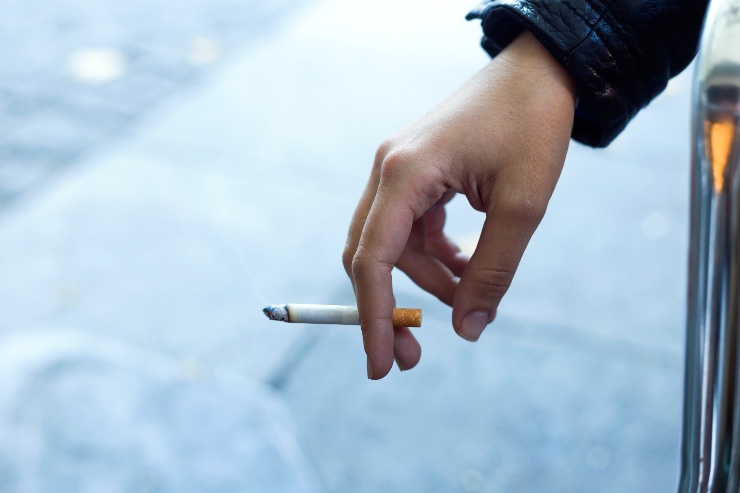Una persona tiene una sigaretta accesa tra le dita