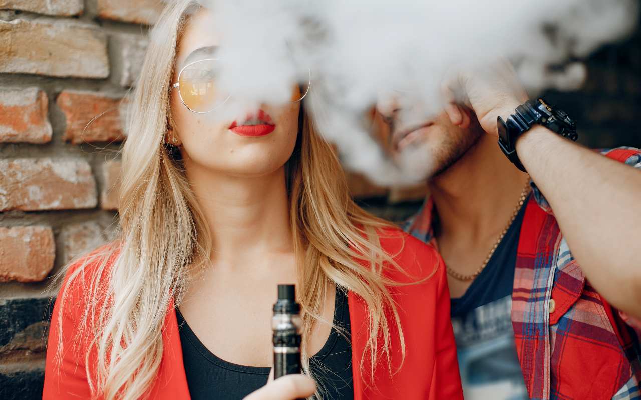 Due persone fumano la sigaretta elettronica circondati dal fumo