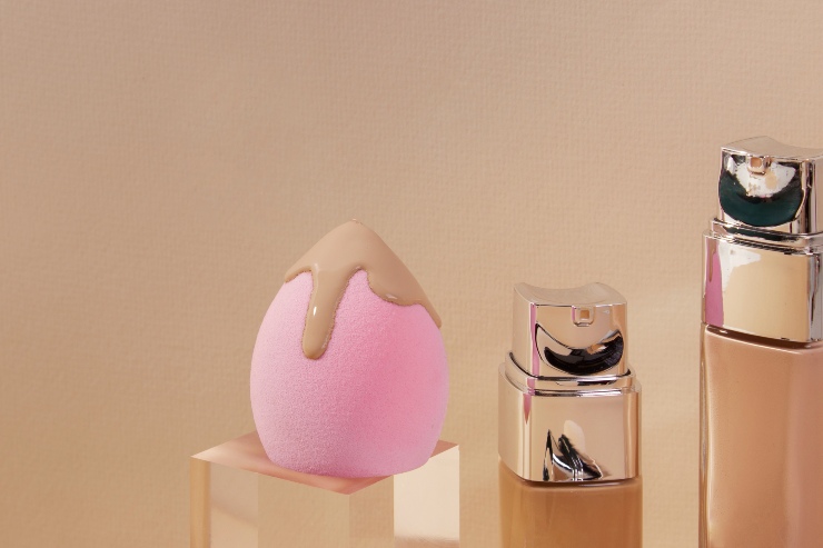 Spugnetta beauty con fondotinta vicino a dei trucchi