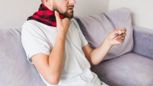 Una persona con il mal di gola tiene in mano un termometro