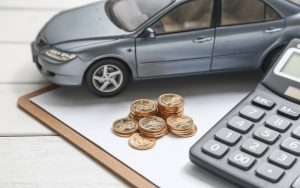 Un modellino di un'auto, monete, calcolatrice e moduli su un tavolo