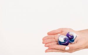 Una persona tiene in mano due pastiglie per lavastoviglie