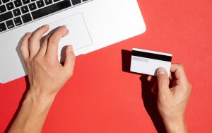 Una persona utilizza il computer mentre tiene in mano una carta di credito