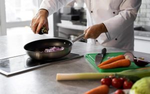 Uno chef prepara un soffritto di cipolle in padella