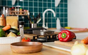 Vista di un piano cottura in cucina con peperoni, verdure e una padella