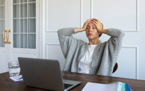Una donna con mal di testa seduta alla scrivania davanti al pc