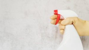 Una persona con un guanto per le pulizie tiene in mano un detersivo spray