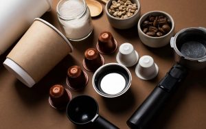 Caffè in capsule e chicchi su un tavolo accanto a bicchieri e strumenti vari
