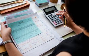 Una persona impegnata a fare i conti con una calcolatrice e fogli in mano