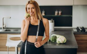 Una donna in tenuta sportiva con una mela in mano in cucina