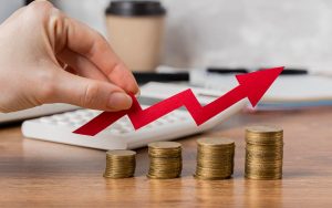 Concetto di investimento finanziario con una mano che tiene una freccia rossa verso l'alto sopra delle monete