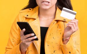 Una donna preoccupata tiene in mano una carta di pagamento e uno smartphone